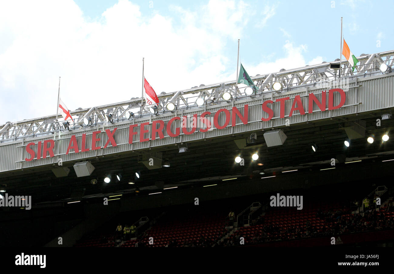 Une vue générale des drapeaux en berne au-dessus de la Sir Alex Ferguson, restent debout pendant le témoignage de Michael Carrick match à Old Trafford, Manchester. Banque D'Images