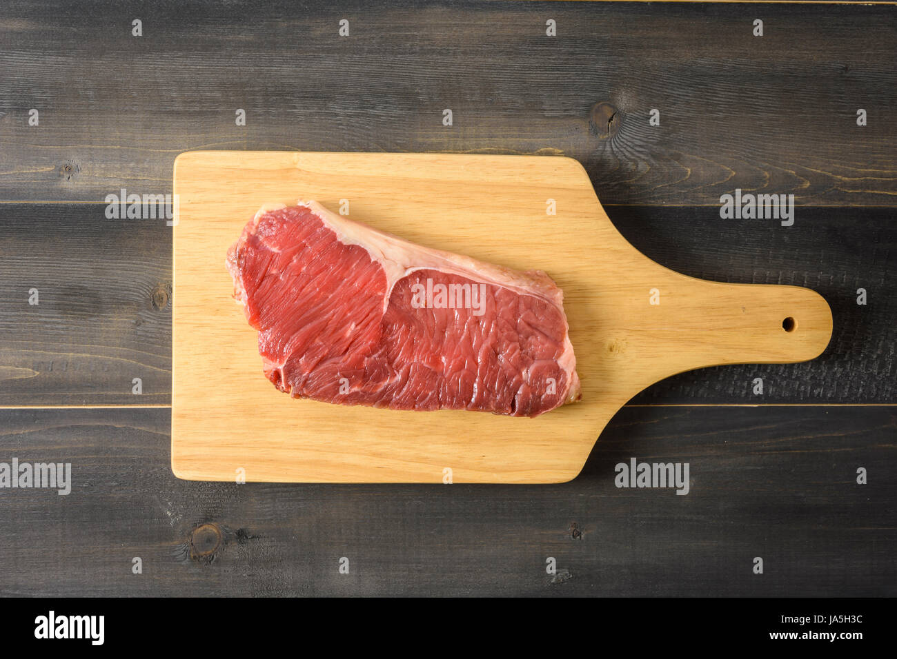 Faux filet de boeuf cru steak sur une planche à découper en bois, vue du dessus sur Banque D'Images