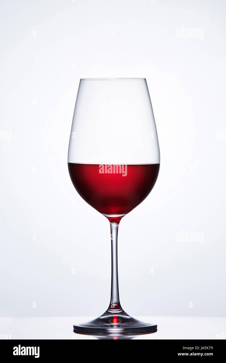 Verre à vin cristal élégant avec du vin rouge à l'arrière-plan clair avec la réflexion. Banque D'Images