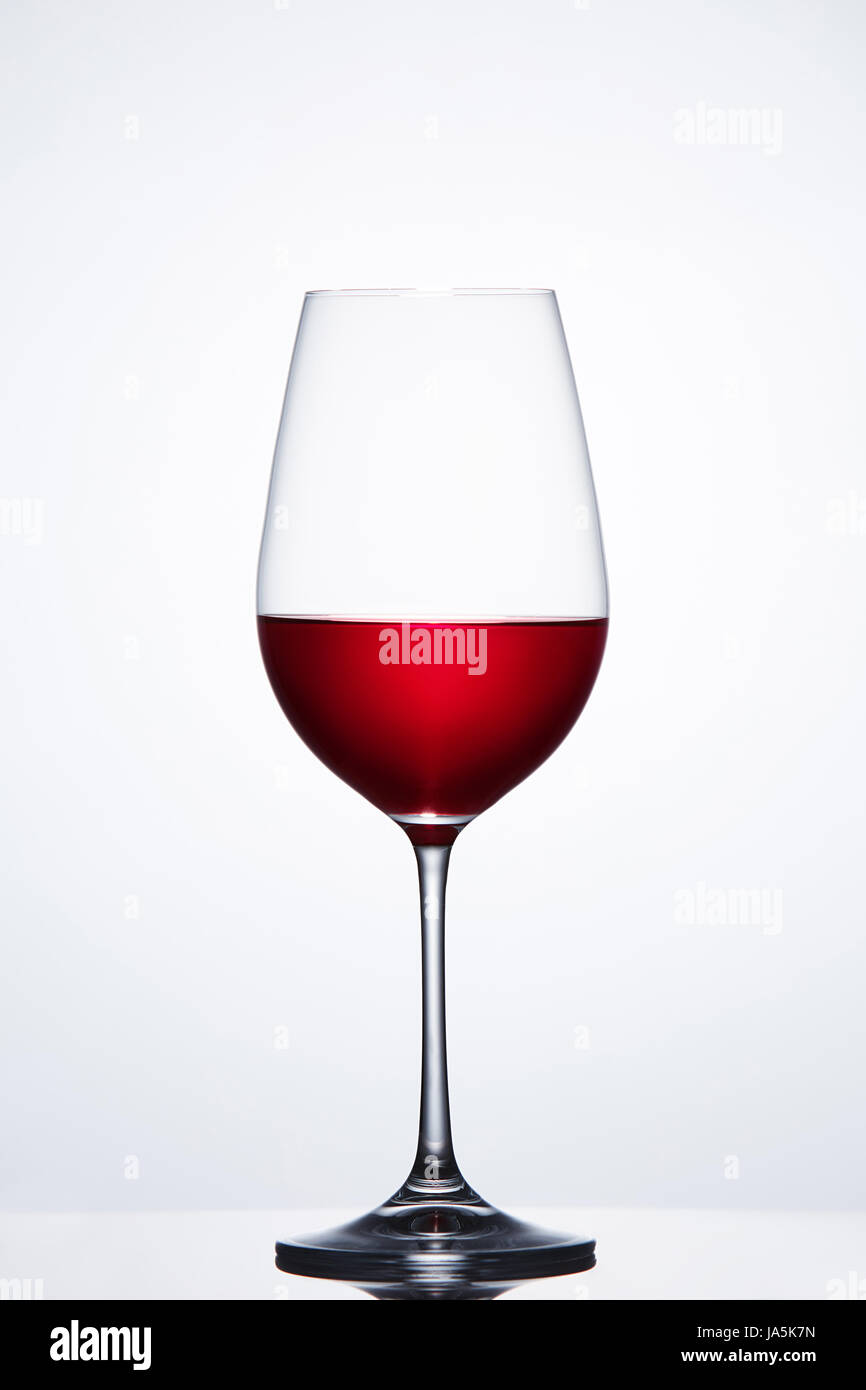 Vin rouge dans le verre pur fragile contre la lumière permanent bckground avec réflexion. Banque D'Images