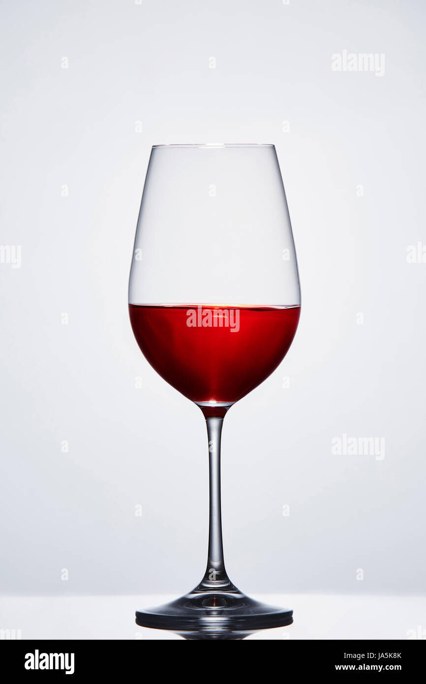 Halffull avec verre de vin pur vin vin rouge contre l'arrière-plan clair avec la réflexion. Banque D'Images