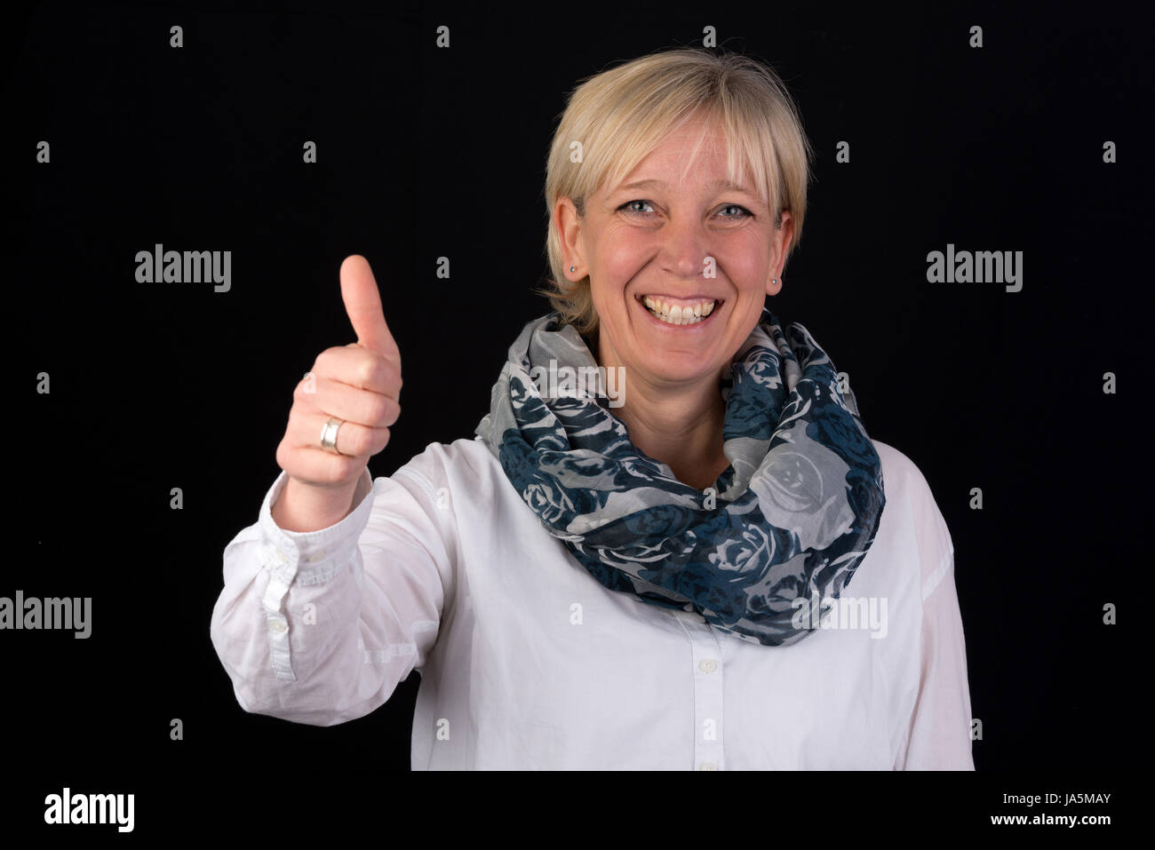 Belle blonde mature woman giving thumbs-up comme signe positif Banque D'Images