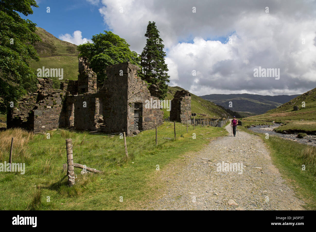Female hiker en passant devant les ruines d'un bâtiment sur le chemin, menant Watkin à Snowdon, le plus haut sommet dans le parc national de Snowdonia au Pays de Galles. Banque D'Images