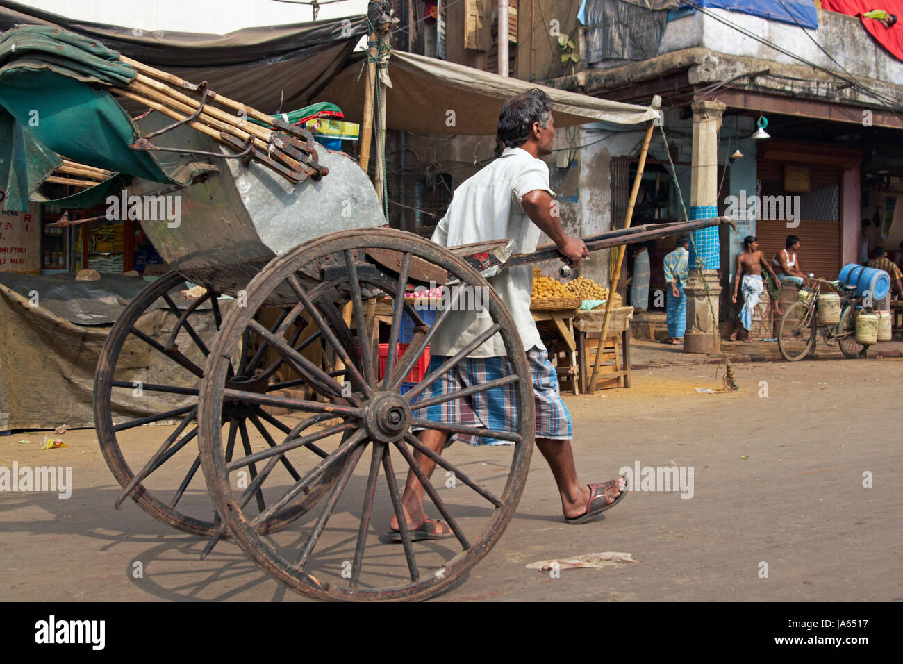 L'homme tire un pousse-pousse tiré traditionnel à la main le long d'une rue à Kolkata, Bengale occidental, Inde. Banque D'Images