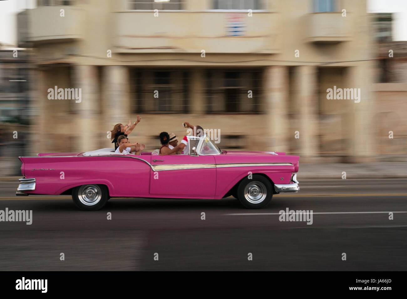 Les touristes la conduite dans une vieille voiture sur le Malecon Banque D'Images