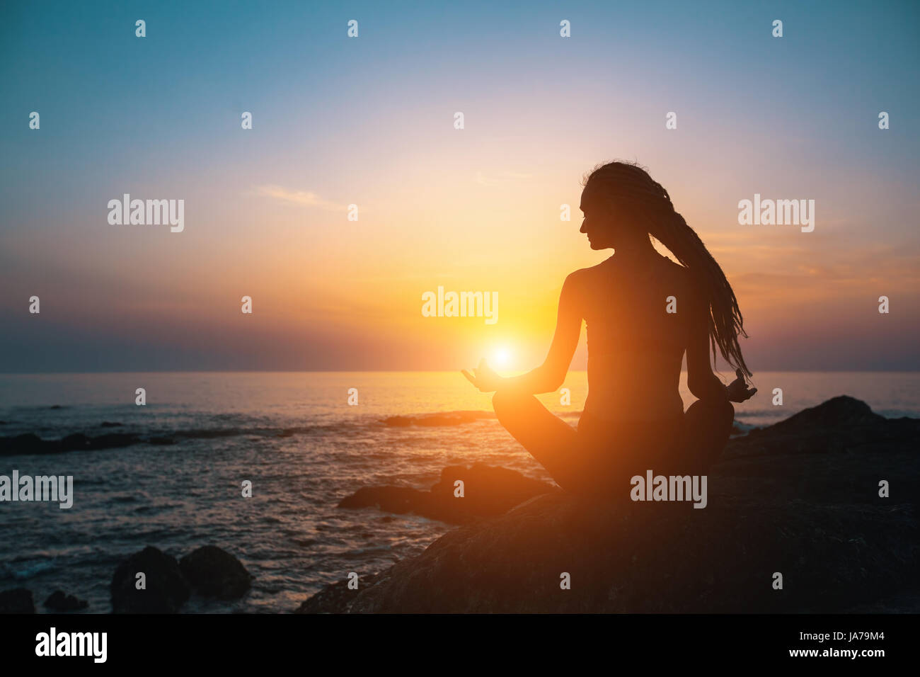Fille de méditation sur la mer au coucher du soleil. Silhouette de yoga. Condition physique et mode de vie sain. Banque D'Images
