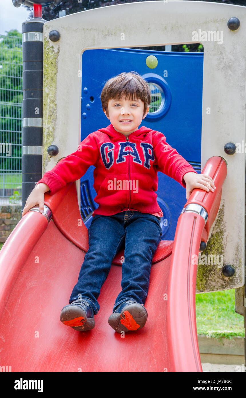 Un jeune enfant jouant dans l'aire de jeux pour enfants dans Prspect Park, lecture. Banque D'Images