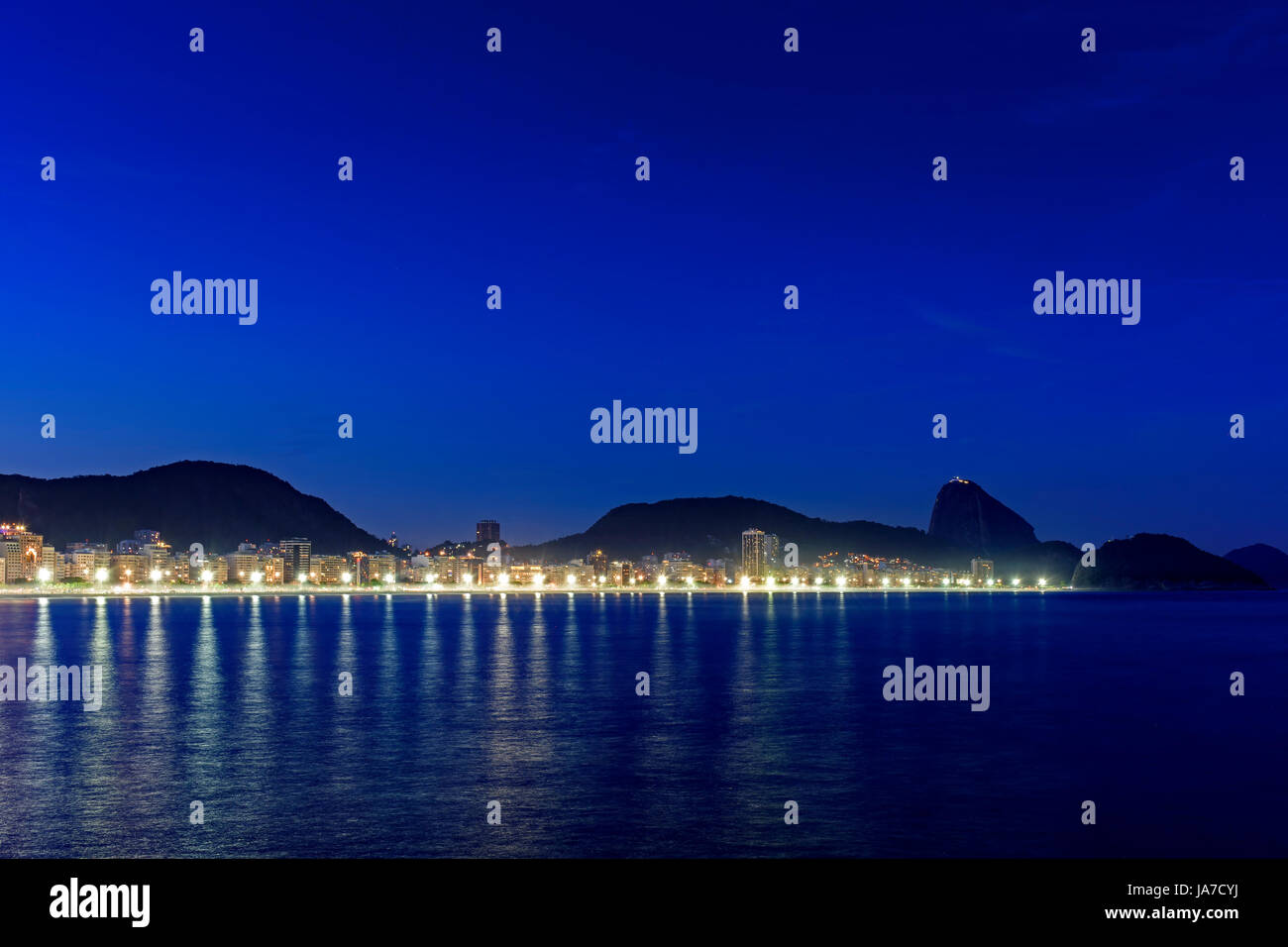 La plage de Copacabana et le Pain de Sucre vu la nuit avec ses bâtiments, l'éclairage, la mer, les collines et les contours Banque D'Images