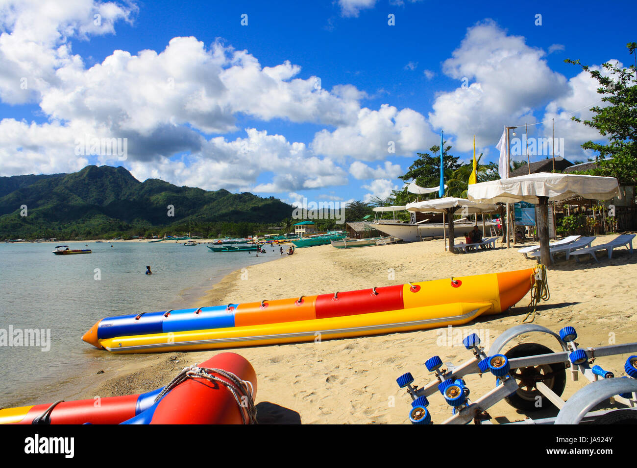 Plage de sable blanc contre un ciel bleu clair, sur la montagne et une activité de l'eau bateau Banque D'Images
