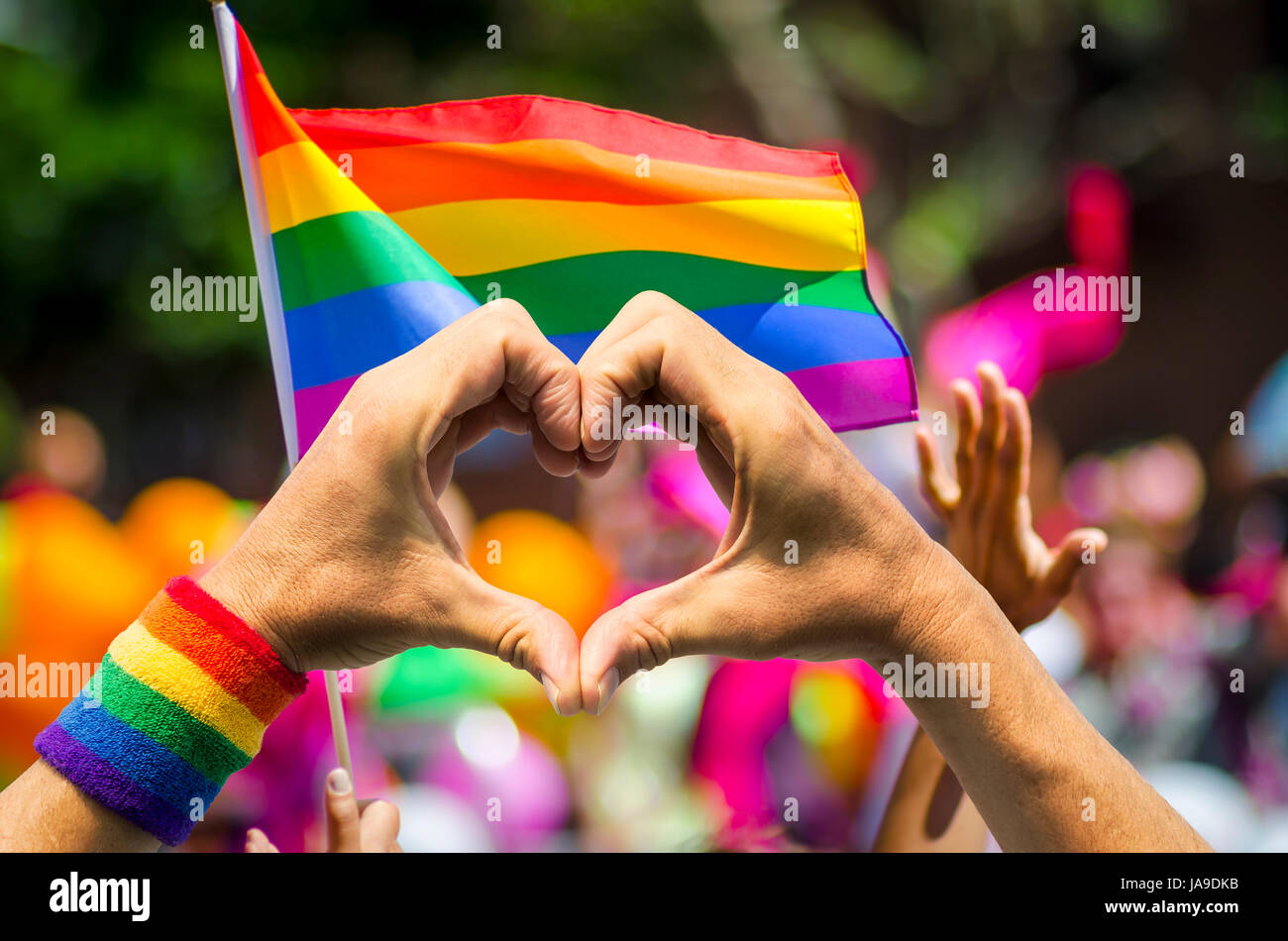 Des mains faire signer et vague à l'avant d'un drapeau arc-en-ciel en marge d'une gay pride parade d'été Banque D'Images