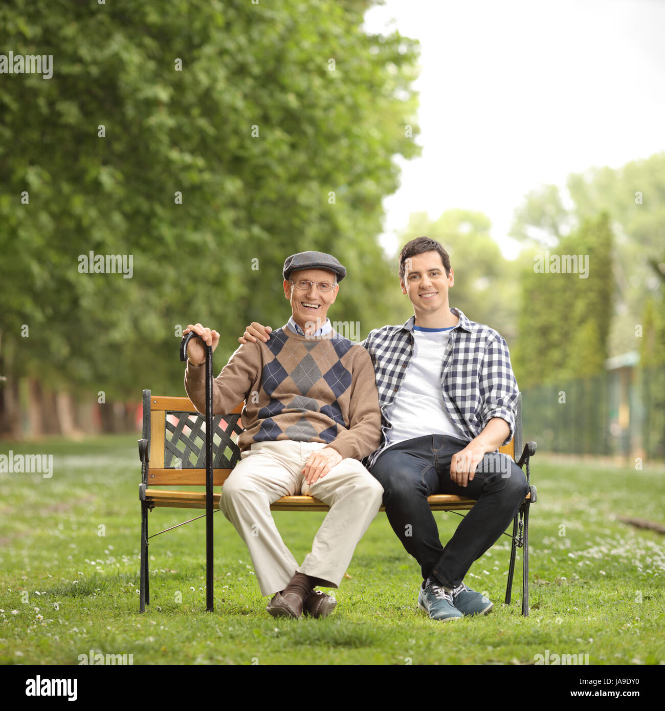 Grand-père avec son petit-fils assis sur un banc dans le parc et à la recherche à l'appareil photo Banque D'Images