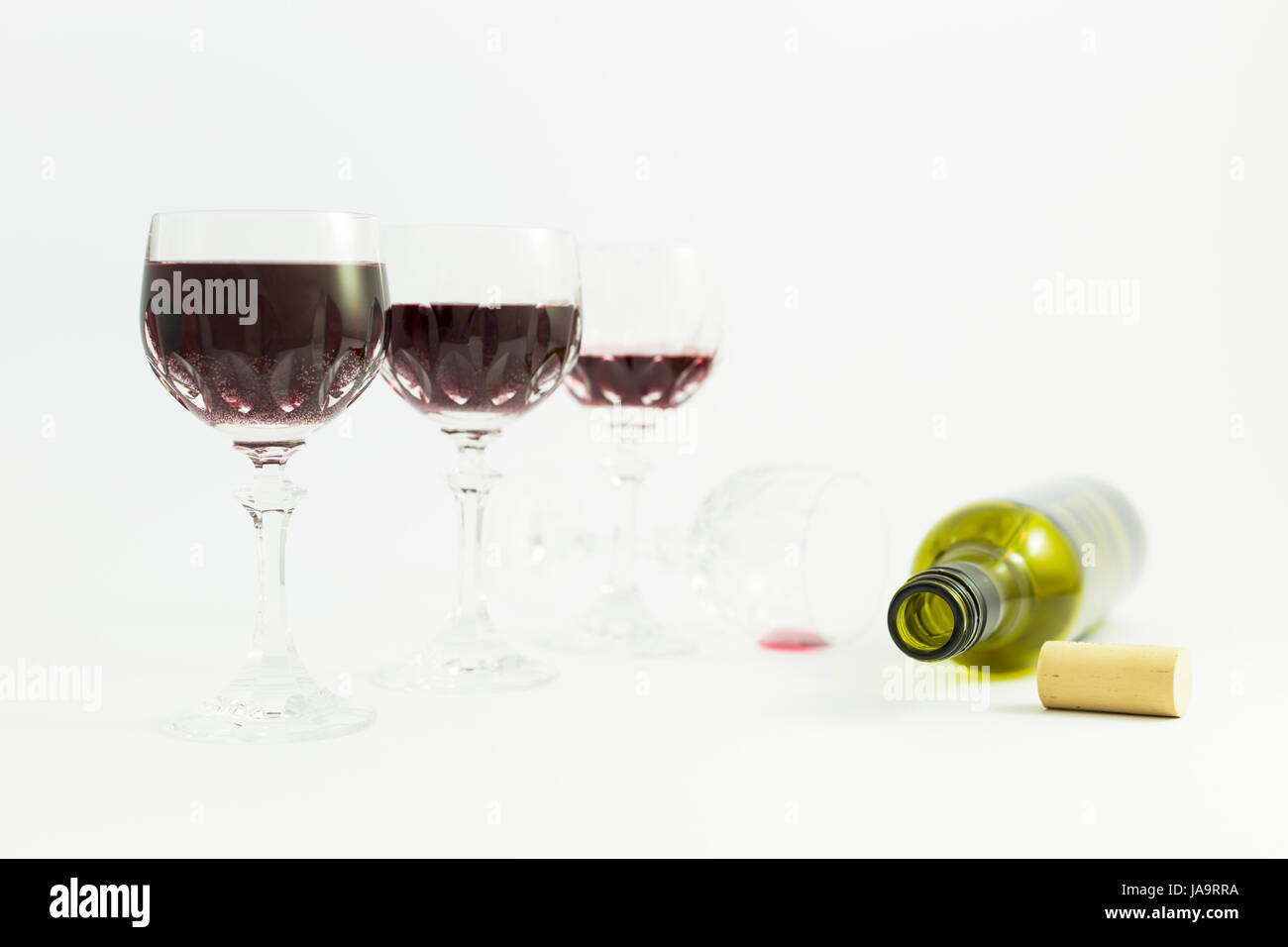 Concept de la consommation d'alcool, l'alcoolisme et l'abus par une ligne de beaux verres de cristal rempli de vin rouge et une bouteille vide. Étapes de drin Banque D'Images