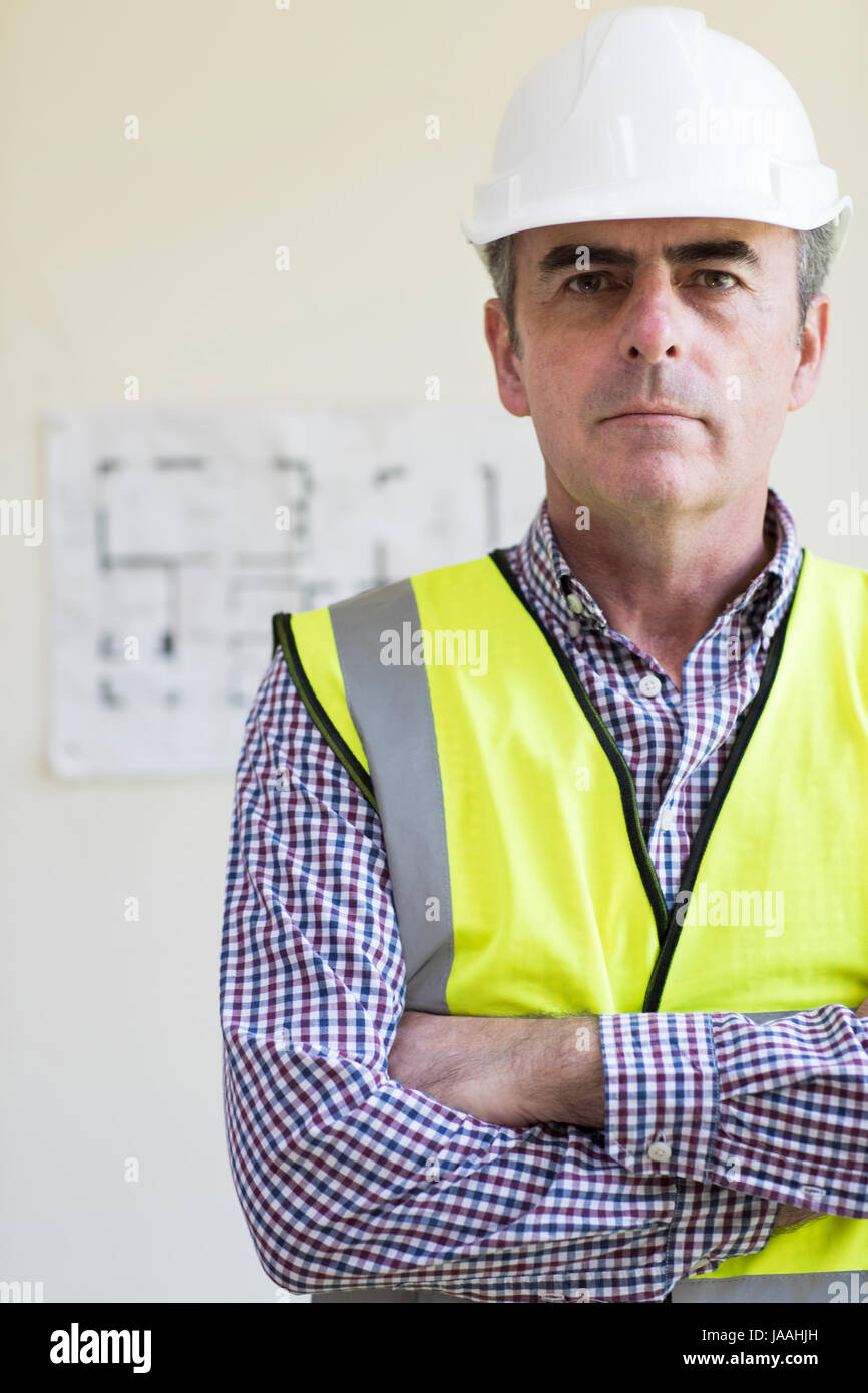 Portrait de l'architecte Wearing Hard Hat avec des plans en arrière-plan Banque D'Images