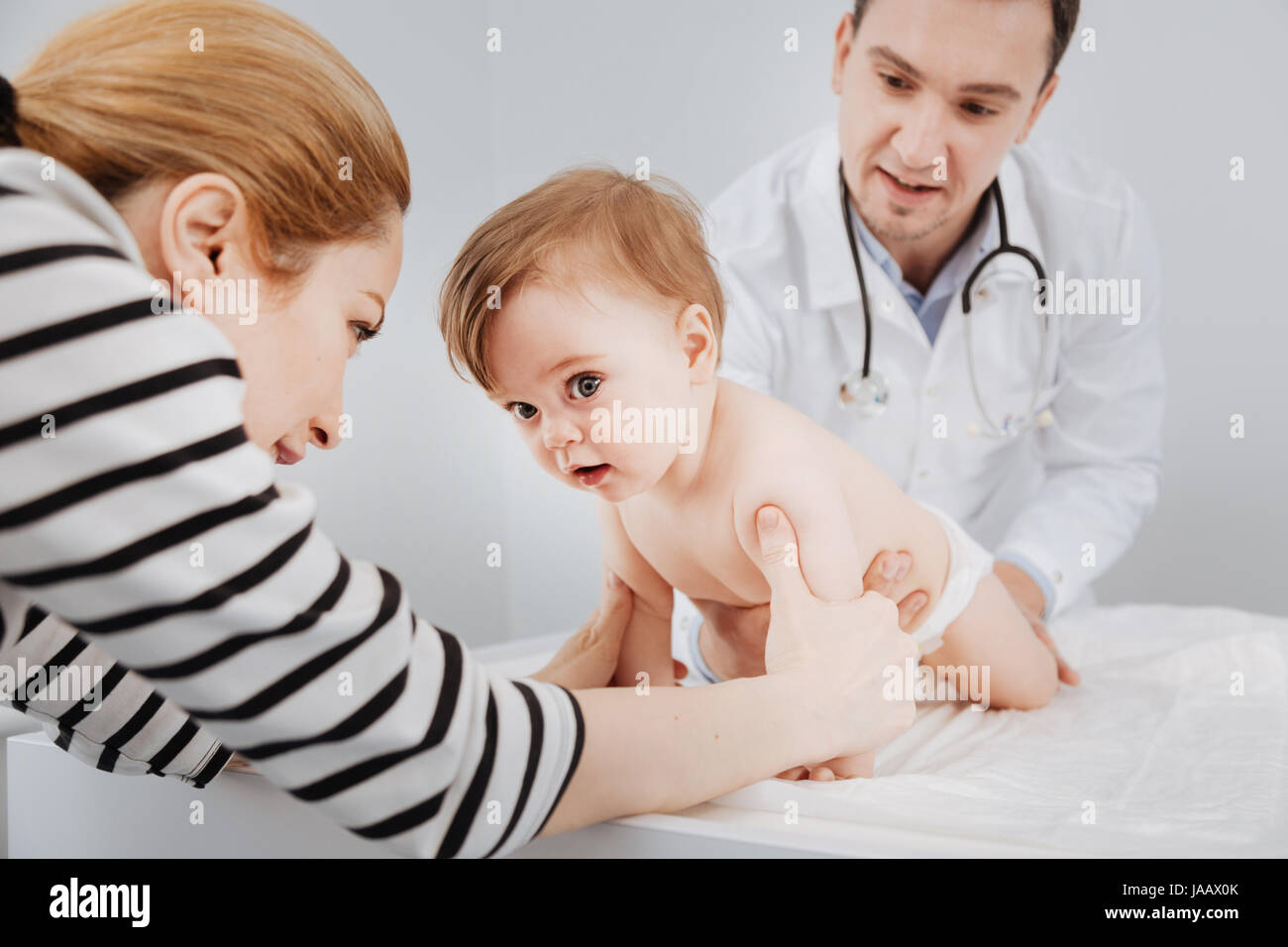 Laissez-nous jouer un peu. Très actif nice kid déménagement tout le temps et sa mère essayant l'attraper et le docteur adorant l'enfant Banque D'Images