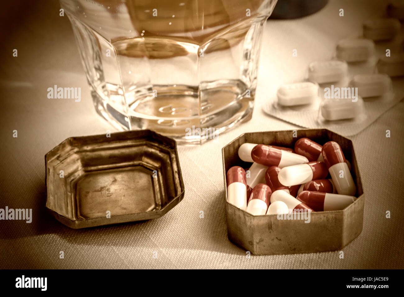 Casemate métallique vintage avec capsules blanches et rouges avec l'eau verre Banque D'Images