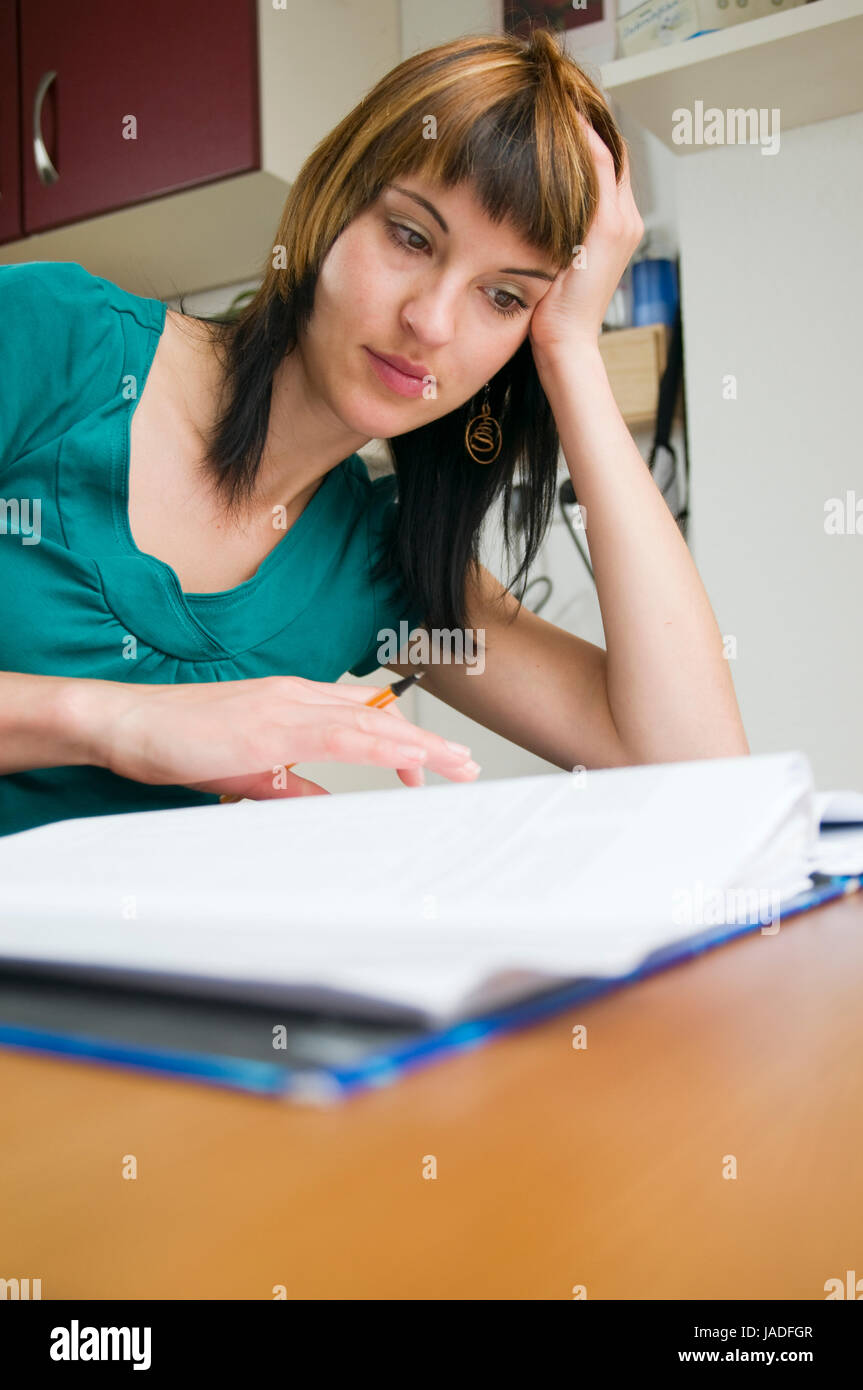 Kopf-und-Schulter-Ansicht eines jungen Frau am Tisch, brünetten Schreibstift sitzend mit der und Schnellhefter en main vor sich liegend Banque D'Images