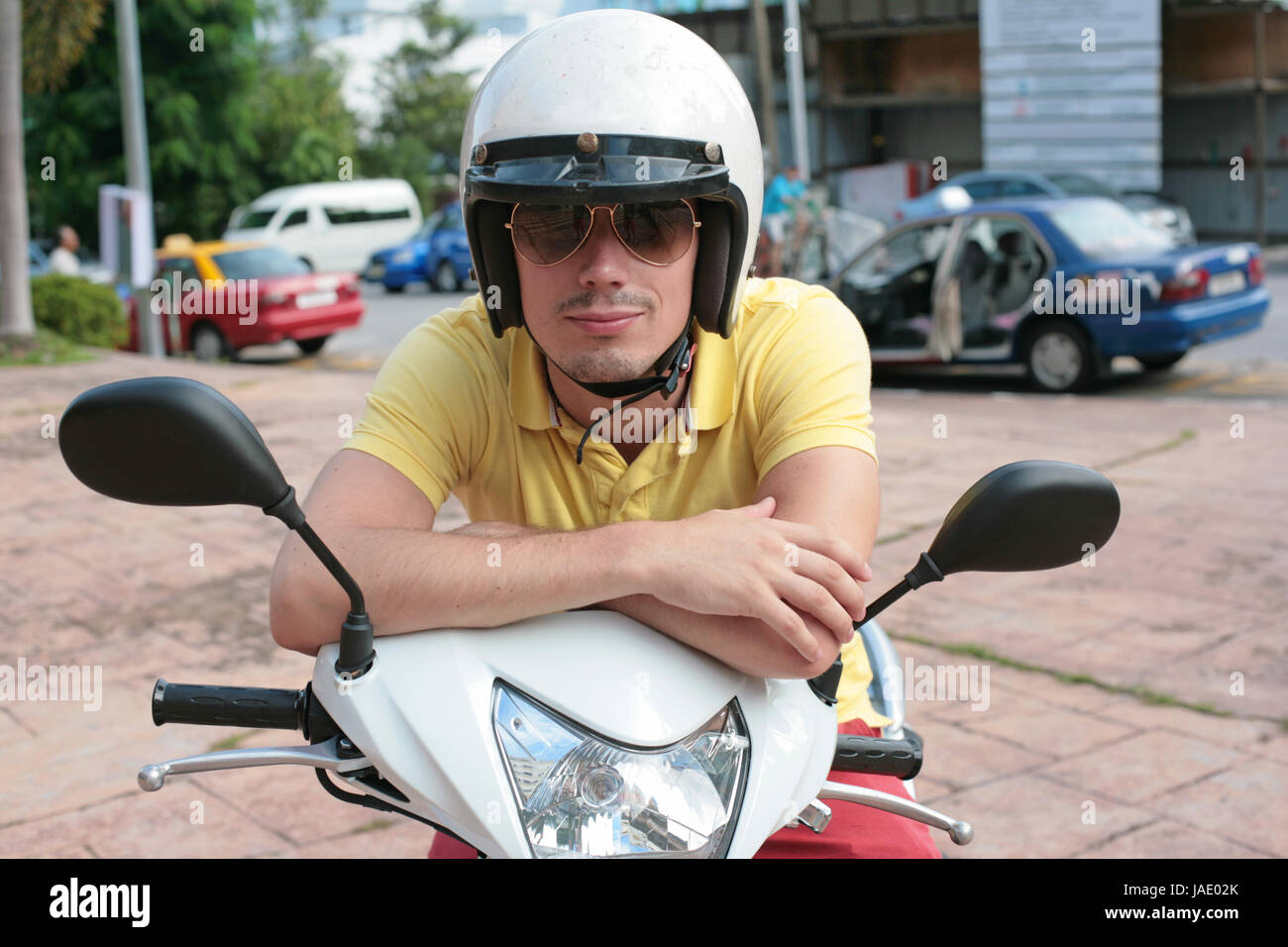 Jeune homme portant des lunettes de soleil sur un scooter Photo Stock -  Alamy