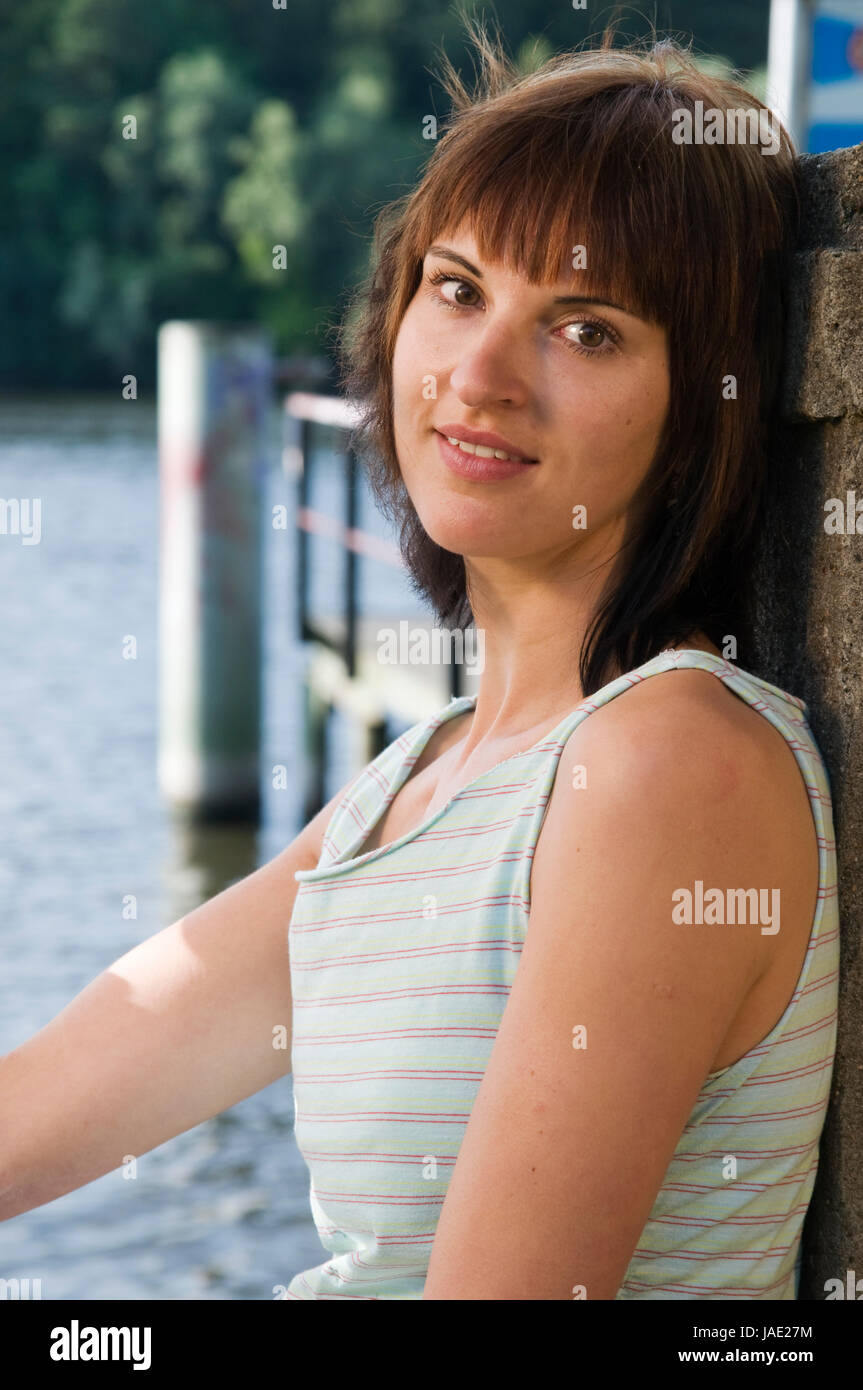 Kopf Seitenansicht-und-Schulter-Porträt eines jungen Frau im ärmellosen brünetten, Oberteil am See mit Blick in die Kamera Banque D'Images