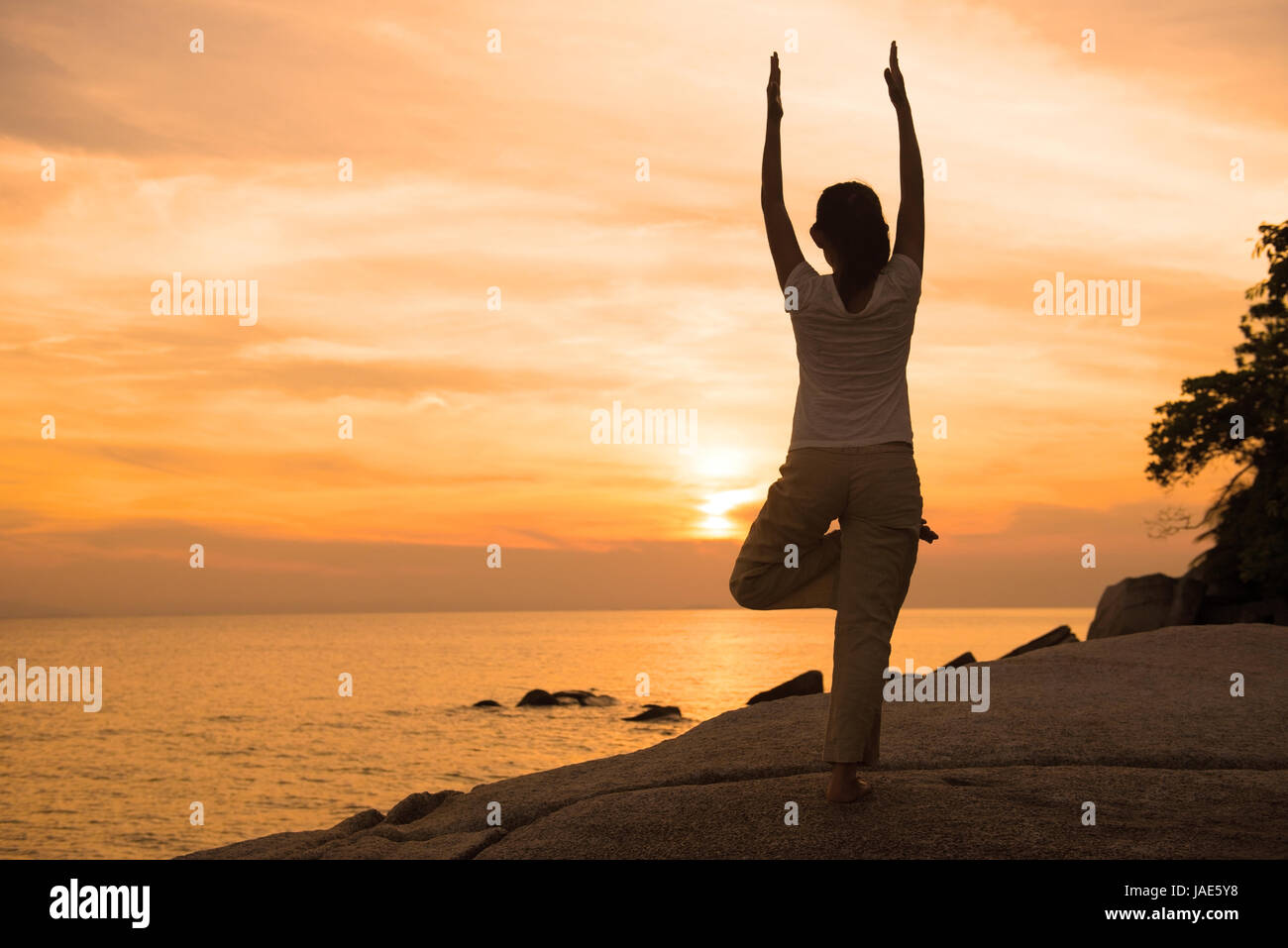 Ossature de jeunes femelles pratiquant le yoga sur la plage au coucher du soleil. Banque D'Images