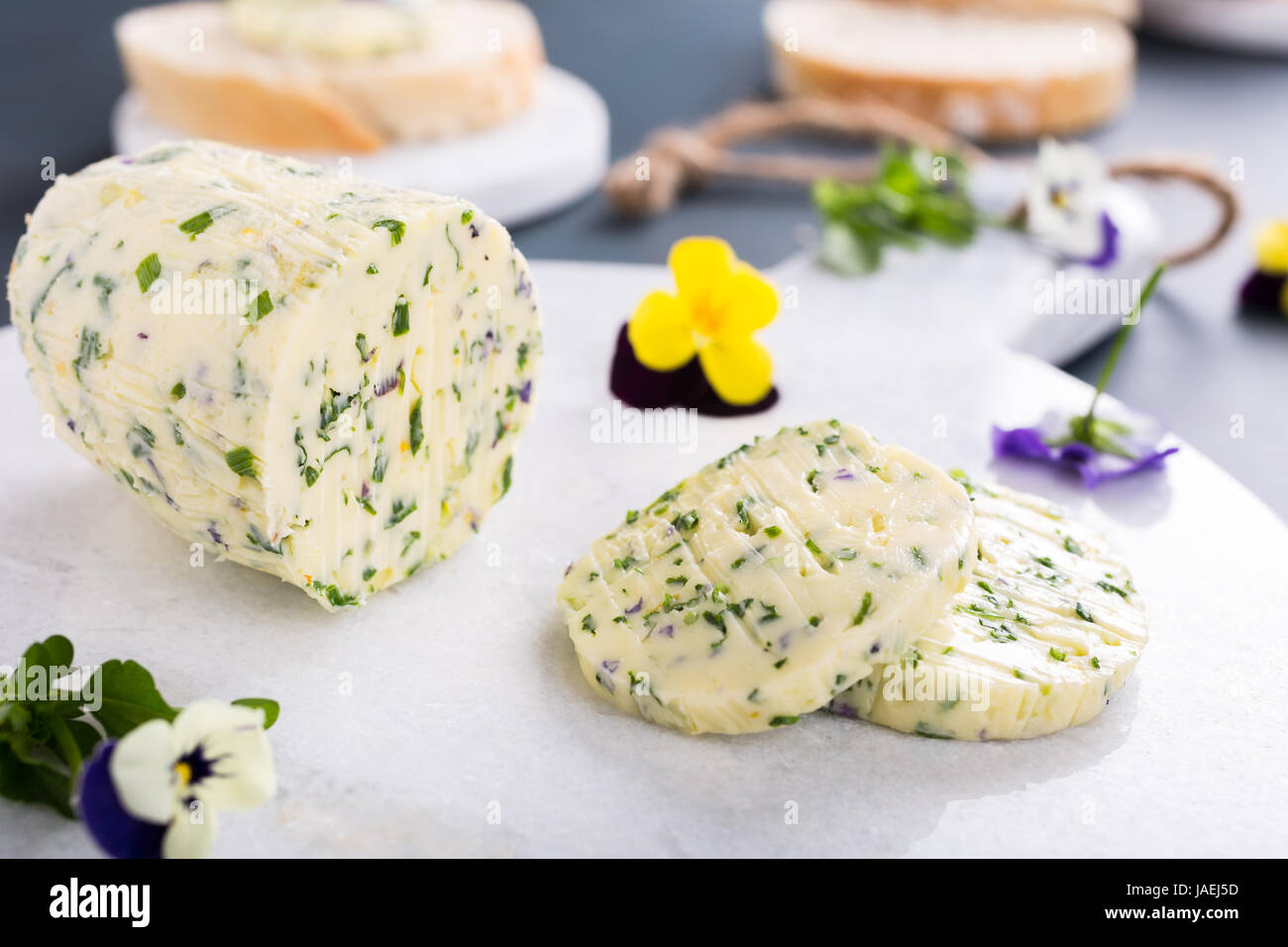 Beurre aux herbes avec des fleurs comestibles sur du marbre à découper, alimentation saine. Banque D'Images