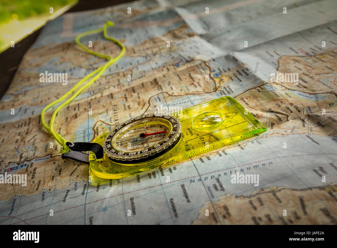 Trouver position avec boussole jaune allongé sur carte touristique sur table en bois situé dans hangar. Banque D'Images