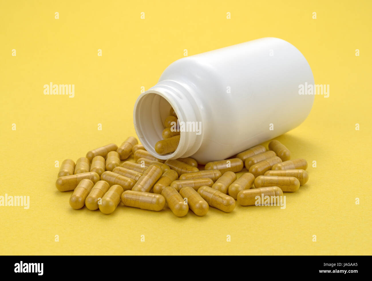 Curcuma de répandre d'une vitamine en plastique blanc bouteille sur un fond jaune. Banque D'Images