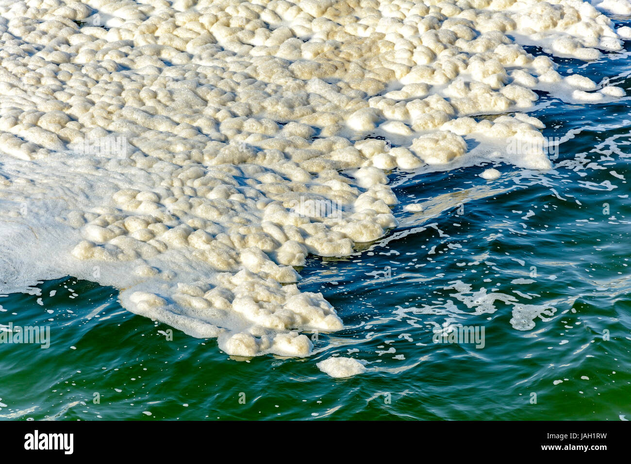 Spot sale pollution spumeux flottant sur les eaux de mer Banque D'Images