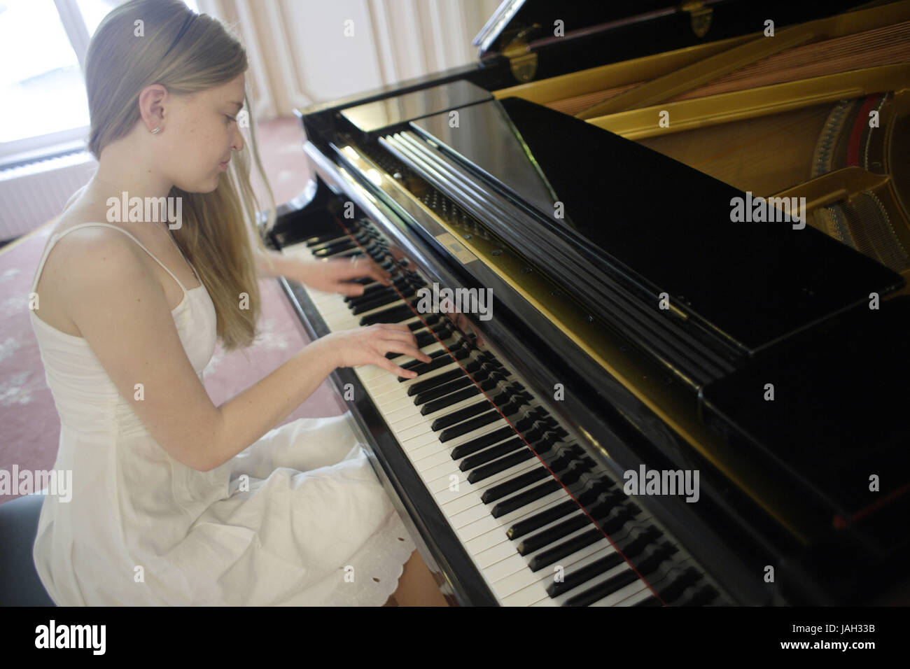 Fille en robe blanche joue du piano, Banque D'Images