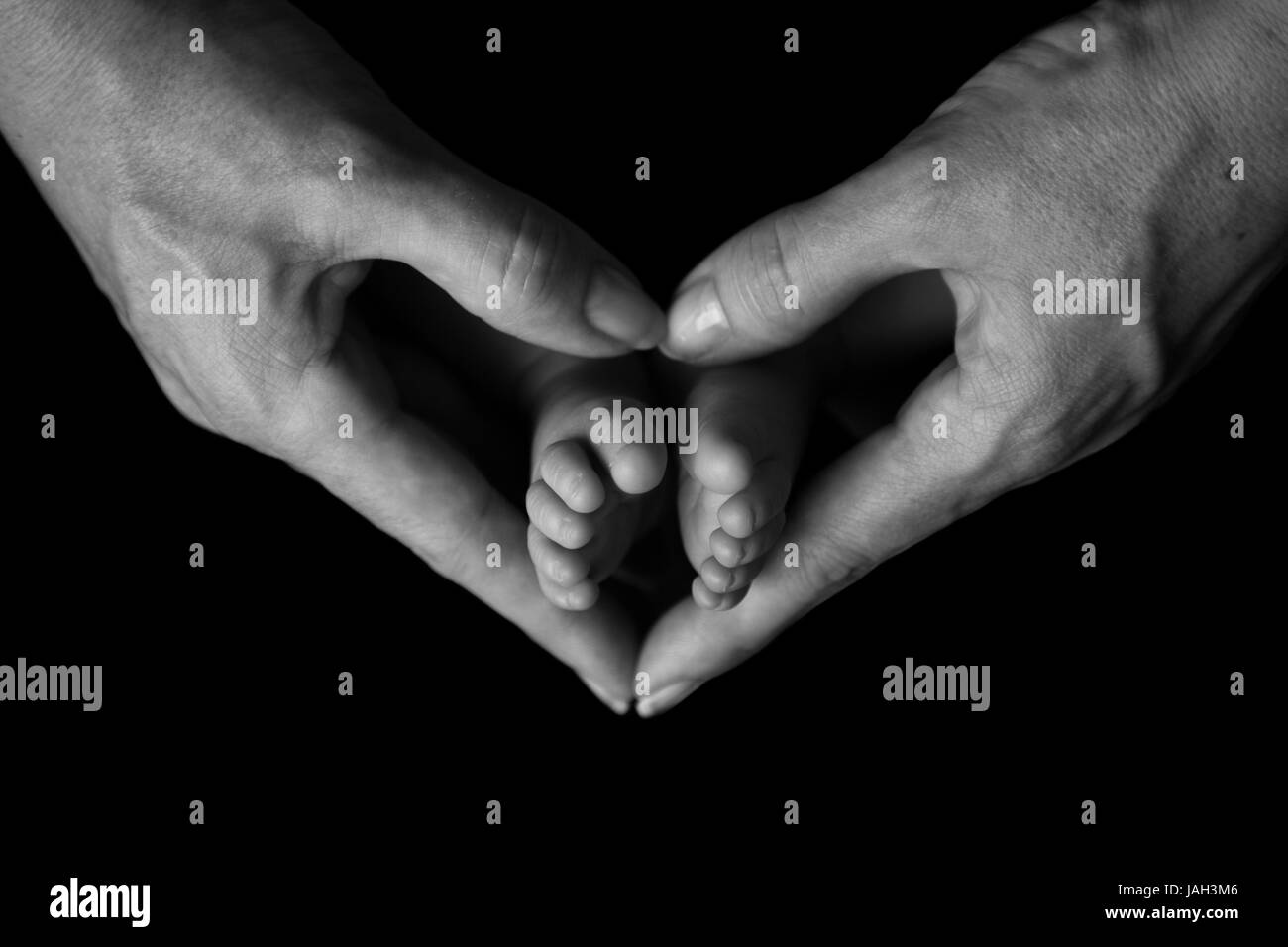 Pieds de bébé dans les mains du cœur des mères Banque D'Images