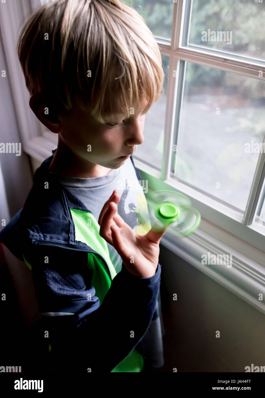 Un garçon joue avec un spinner fidget à la maison, le controversé stress relief toy pour aider certains enfants autistes antsy ou se concentrer à l'école Banque D'Images