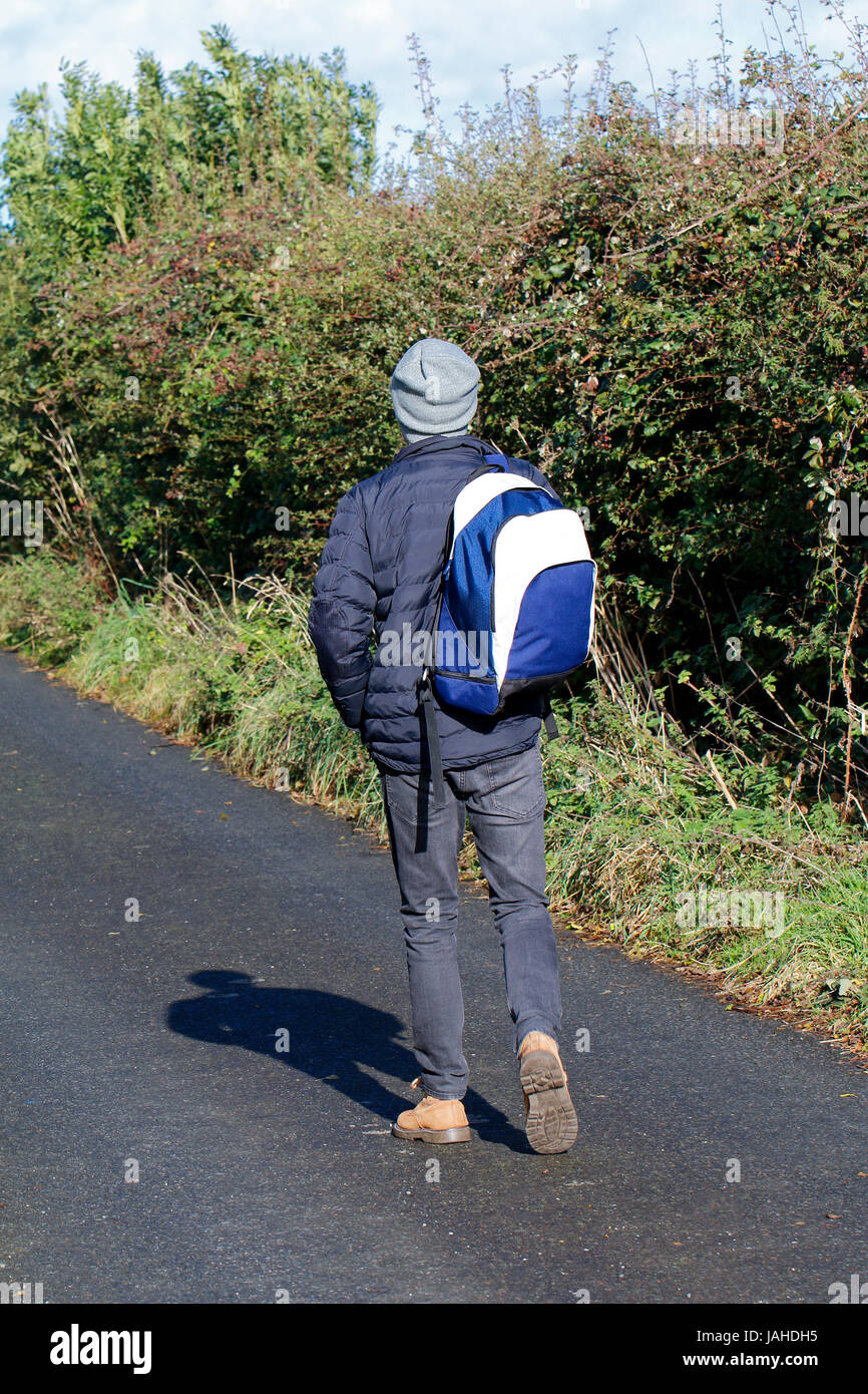 Young man carrying backpack marche loin de la caméra Banque D'Images