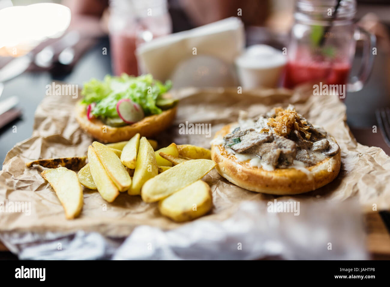 Burger avec des morceaux de boeuf, oignons frits, pommes de terre et légumes. Banque D'Images