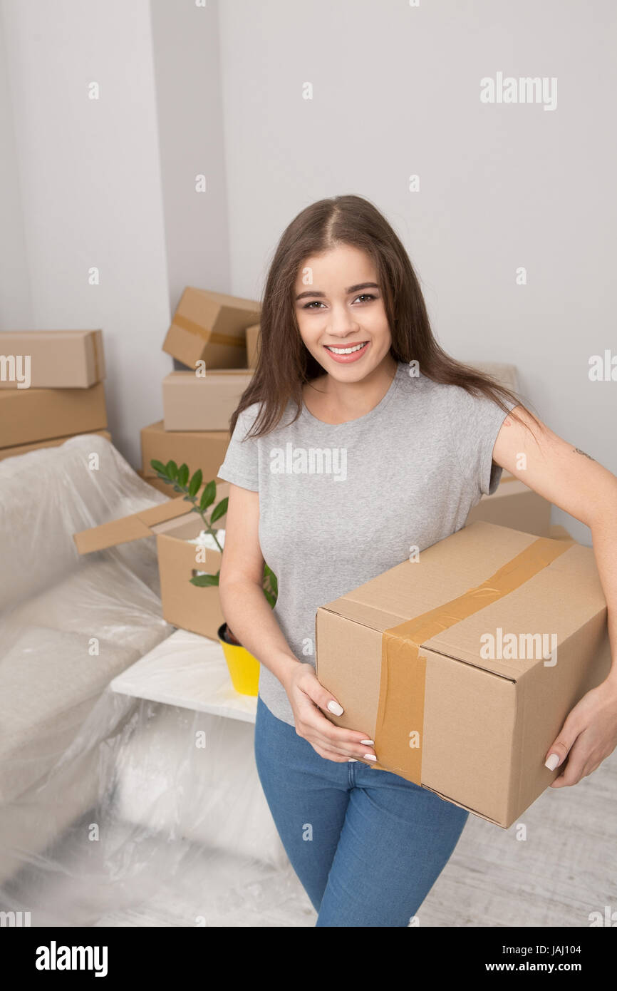 Jeune femme déménager, holding box prêt à déballer les choses dans les pays nouvellement appartement loué. Banque D'Images