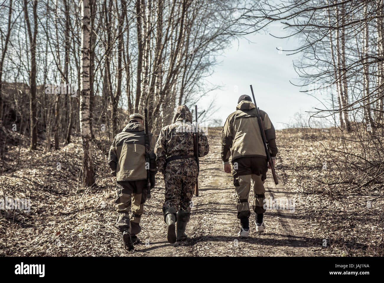 Groupe d'hommes chasseurs qui monte à la route rurale pendant la saison de la chasse Banque D'Images