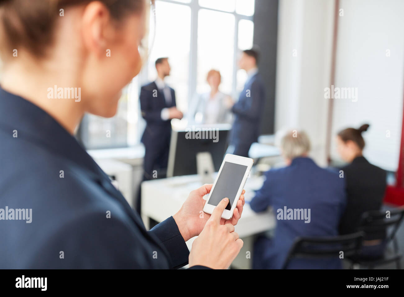 Businesswoman envoie des SMS avec le smartphone lors de réunion d'affaires Banque D'Images