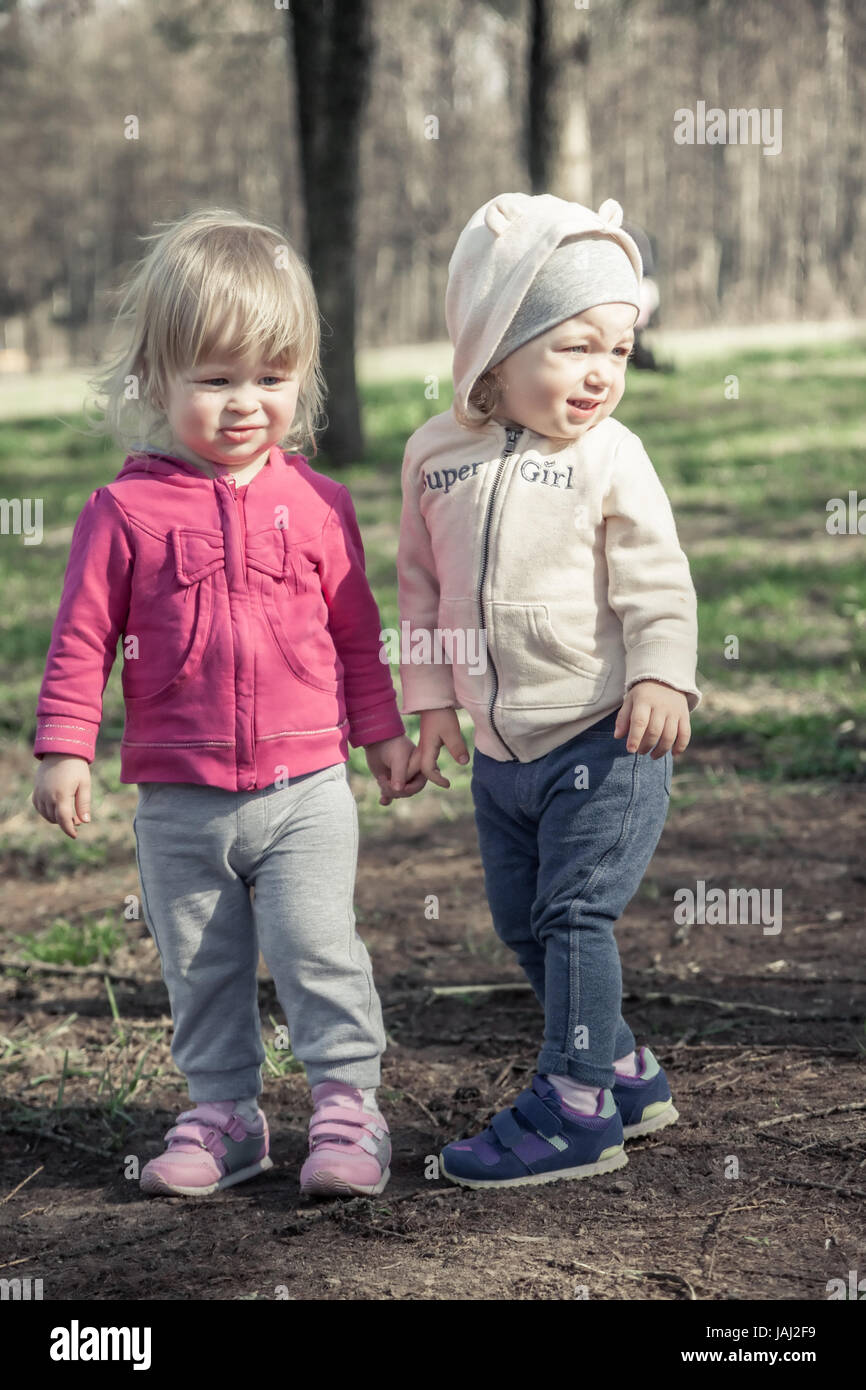 Deux beaux enfants filles maintenant l'ensemble avec les mains en été park symbolisant l'amitié et de l'enfance enfants Banque D'Images
