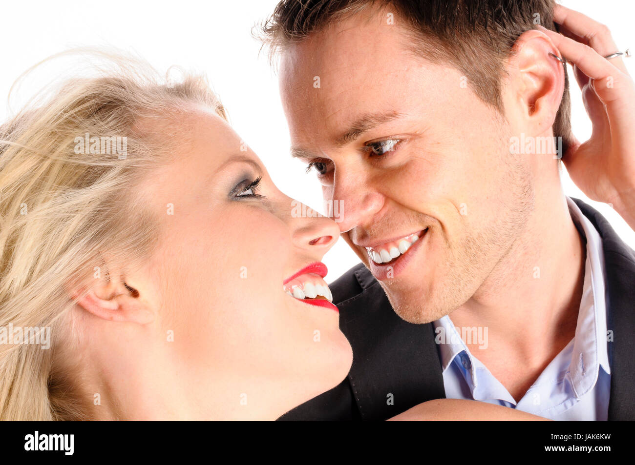 Ein junger Mann im Dunklen Anzug und eine attraktive blonde Frau stehen vor freigestellt weißem Hintergrund, Sie sich und umarmen küssen. Banque D'Images