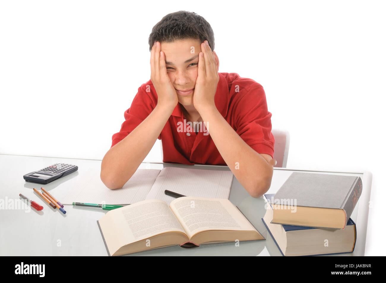 Junge sitzt erschöpft frustriert und über Hausaufgaben am Schreibtisch Hintergrund weißem vor Banque D'Images