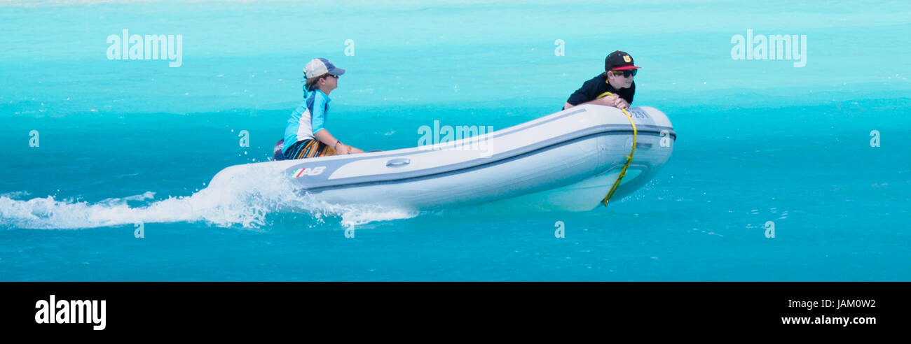 Les garçons s'amuser sur les locations de bateau à bateau crasseux dans les îles Vierges britanniques dans les eaux turquoises de la plage de sable blanc et de palmiers Banque D'Images