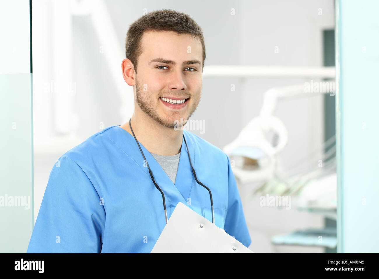 Médecin homme posant et en vous regardant dans un bureau de dentiste avec de l'équipement médical dans l'arrière-plan Banque D'Images