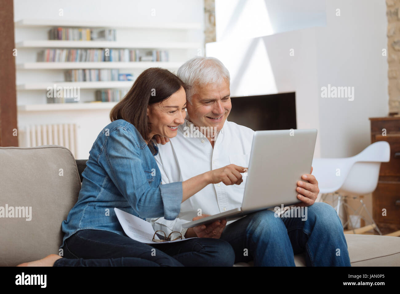 Couple à l'aide de leur ordinateur portable pour payer leurs factures à la maison dans le salon Banque D'Images