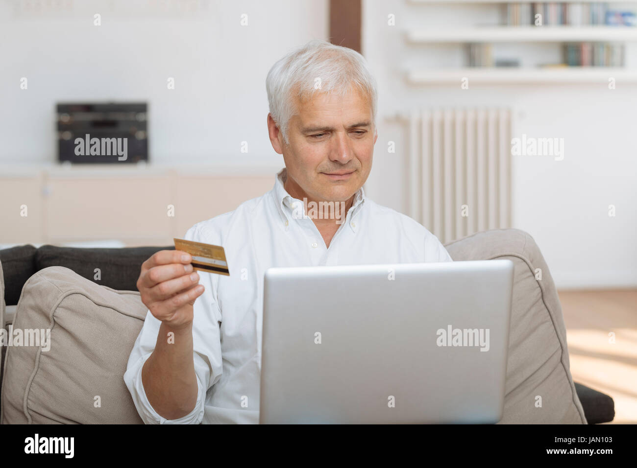 Homme mûr à l'aide de son ordinateur portable et la tenue de sa carte de crédit Banque D'Images