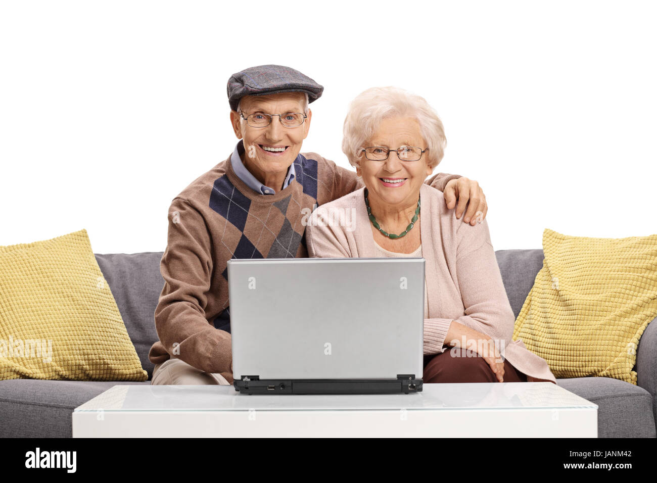 Couple de personnes âgées avec un ordinateur portable assis sur un canapé et regardant la caméra isolé sur fond blanc Banque D'Images