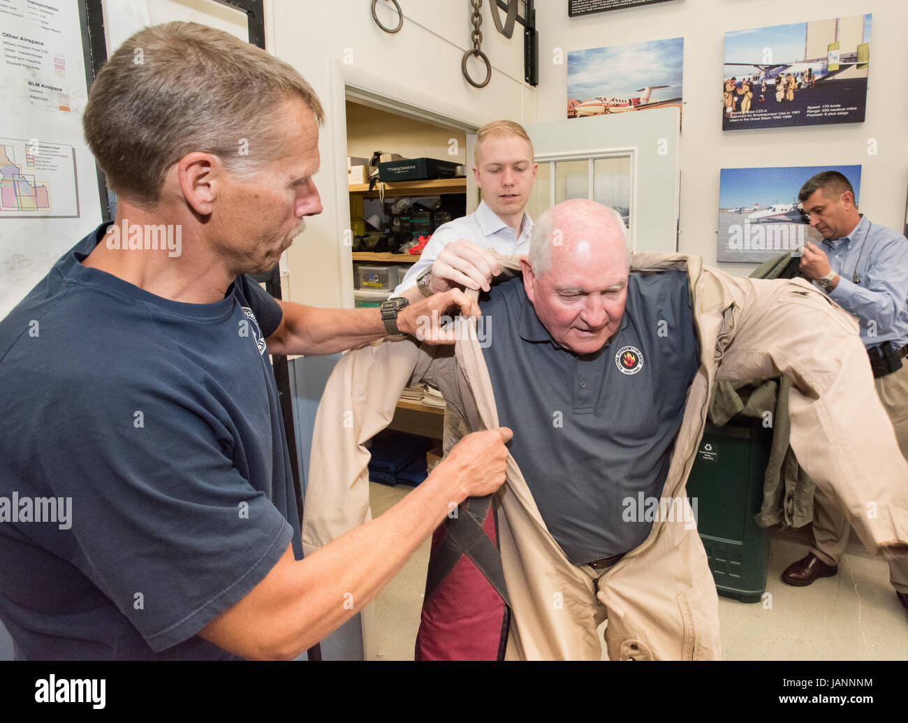 Le Secrétaire à l'Agriculture des États-Unis Sonny Perdue est aidé avec sa combinaison de vol alors qu'il se prépare à rejoindre un groupe d'une traînée d'observer leurs compétences smokejumpers aller au National Interagency Fire Center centre Smokejumpers du Grand Bassin, le 2 juin 2017 à Boise, Idaho. Banque D'Images