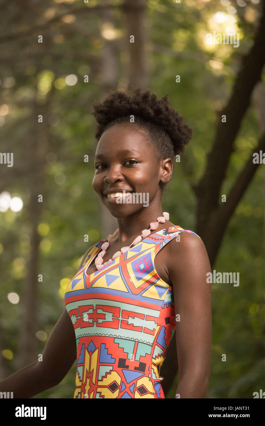 L'un, jeune adulte, black african american happy smiling woman 29 ans, haut du corps tourné, à la recherche d'appareil photo, dehors parc nature, journée ensoleillée, le port Banque D'Images