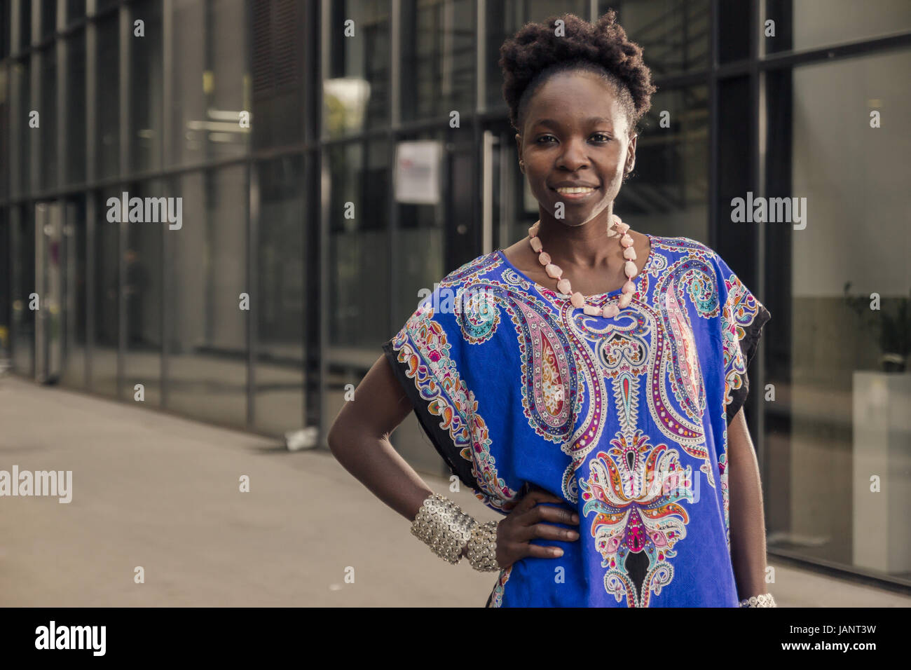 L'un, jeune adulte, black african american woman, 29 ans, gai smiling face, haut du corps tourné, urbaine, du bâtiment, à la recherche d'appareil photo, out Banque D'Images