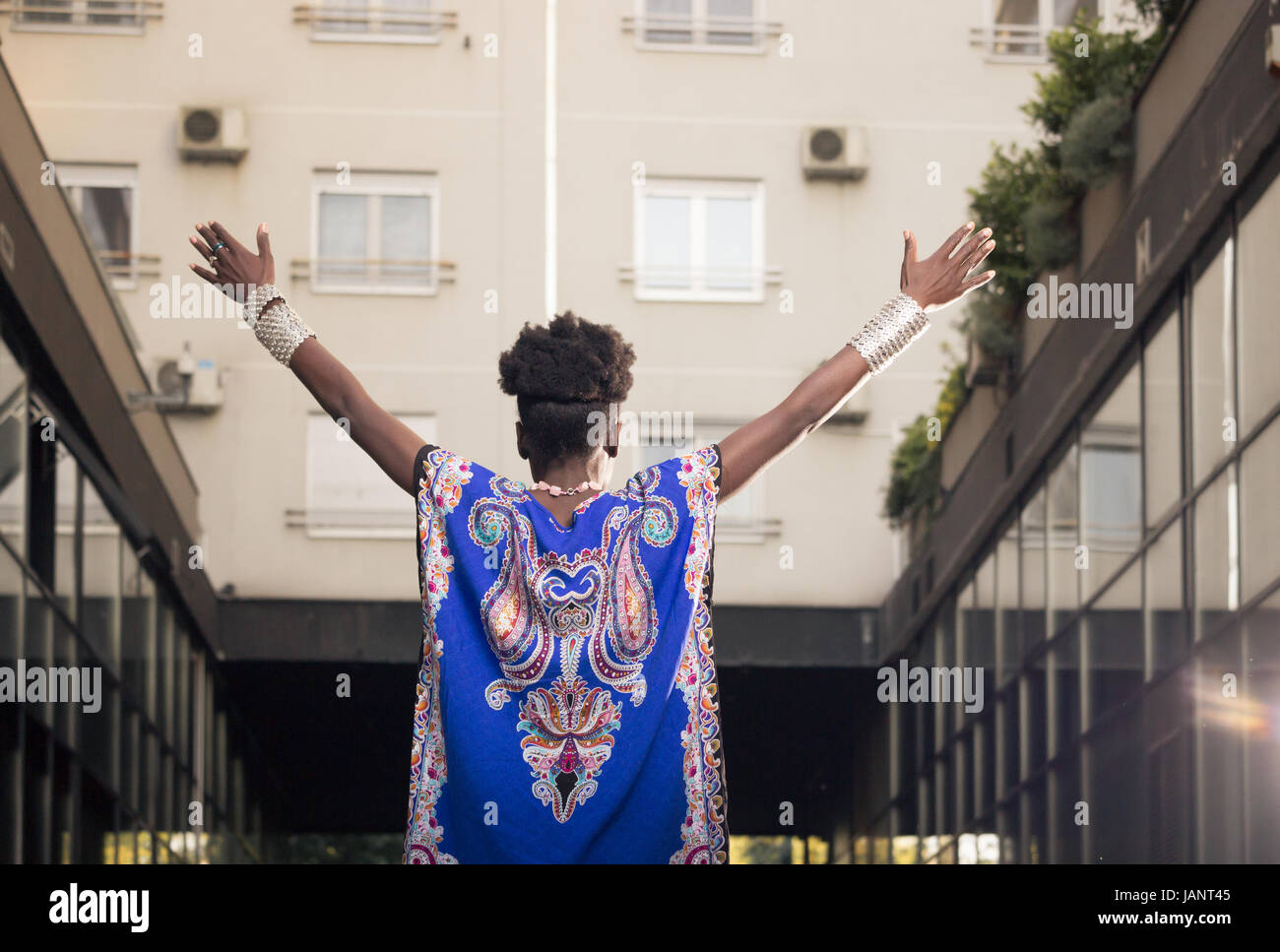 L'un, jeune adulte, black african american woman, 29 ans, bras outstreched, haut du corps tourné, zone urbaine, les bâtiments extérieurs, low angle view, pis Banque D'Images