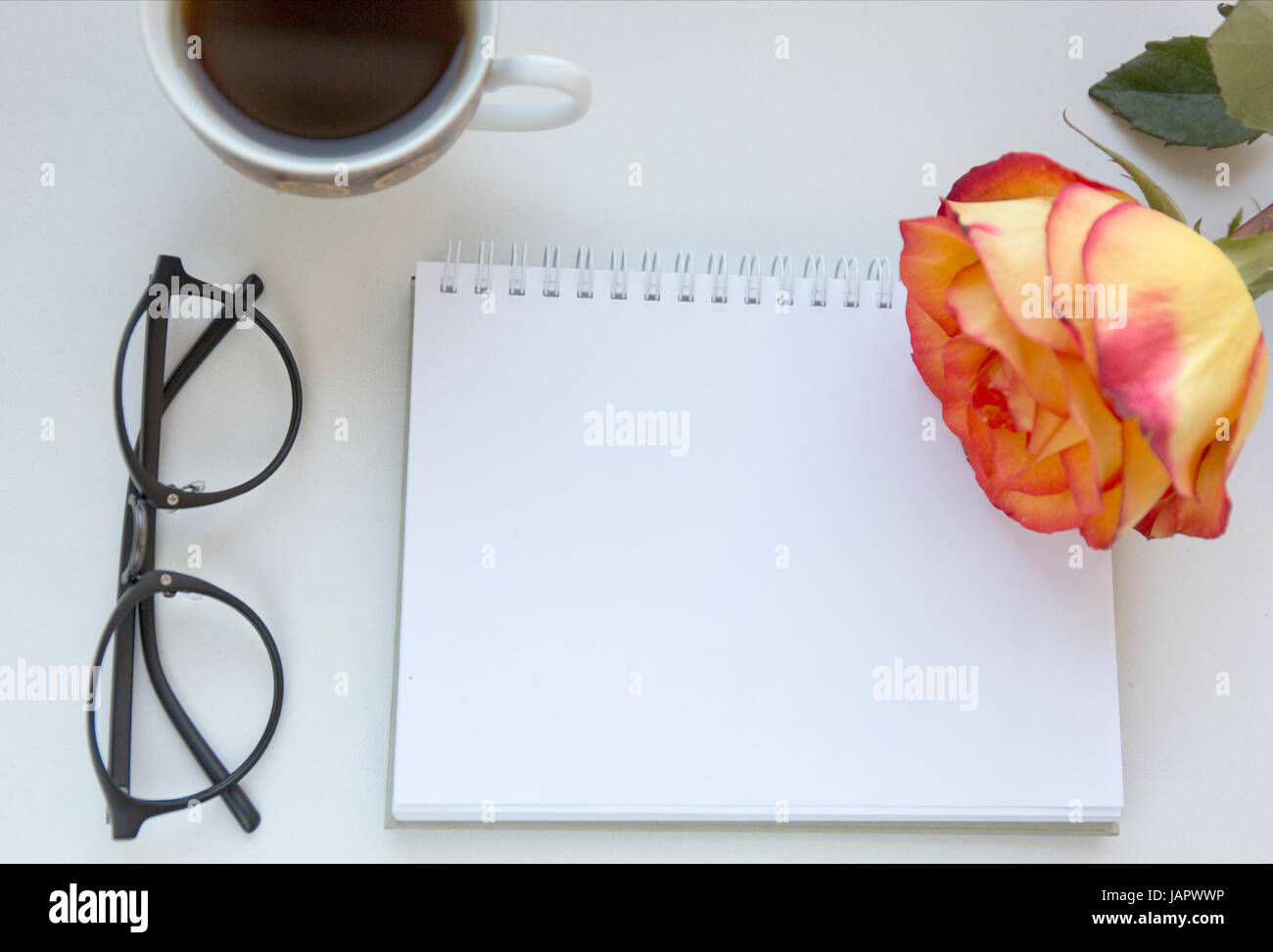 La maquette de l'ordinateur portable de l'art en rouge et jaune rose, verres et tasse de café noir. Vue d'en haut. Place pour le texte. Des fleurs Banque D'Images