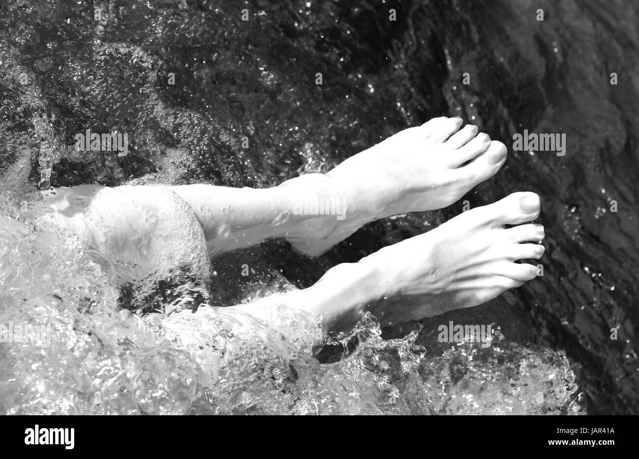 Femme aux pieds nus dans la piscine du spa pendant une session de thérapie de massage avec effet noir et blanc Banque D'Images