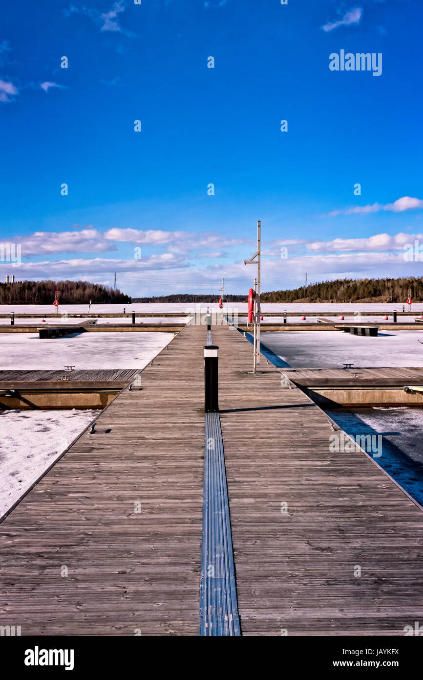 Une jetée en bois sur un lac gelé à Lappeenranta, en Finlande. En été, le quai est plein de petits bateaux à moteur et voiliers. Banque D'Images